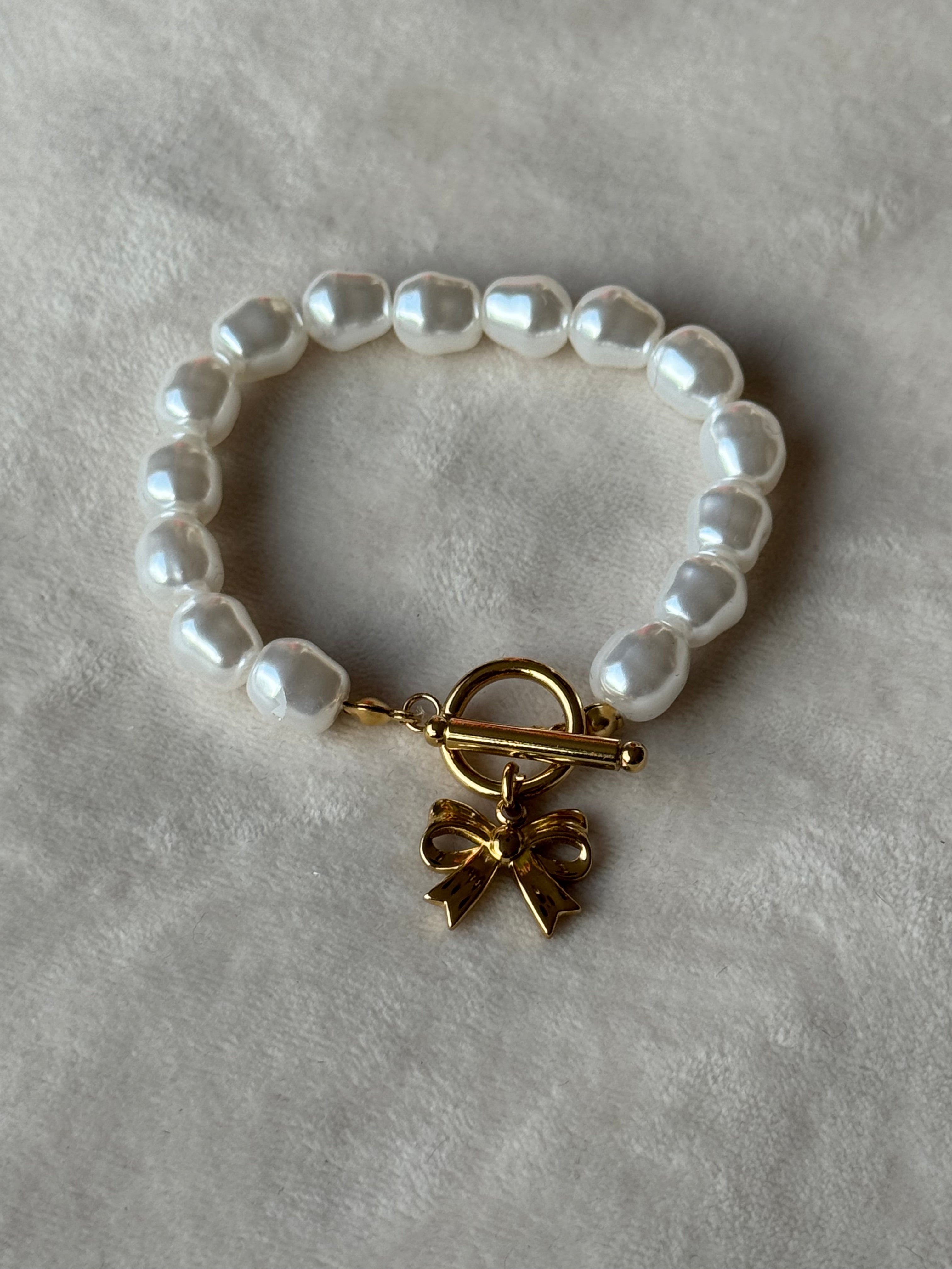 Armband goud/wit parels strikje